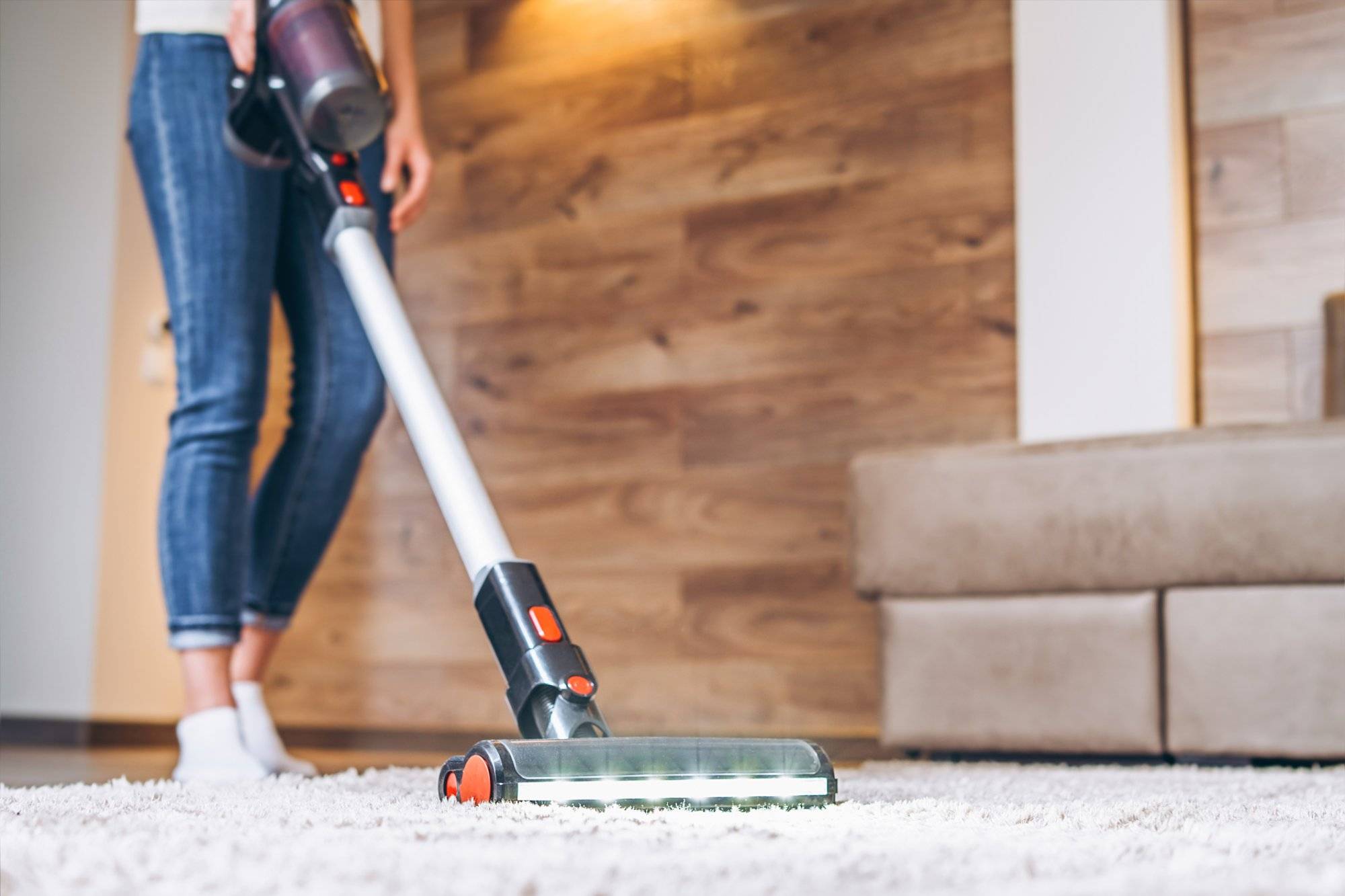 oman cleaning floor and carpet with cordless vacuum cleaner at home.