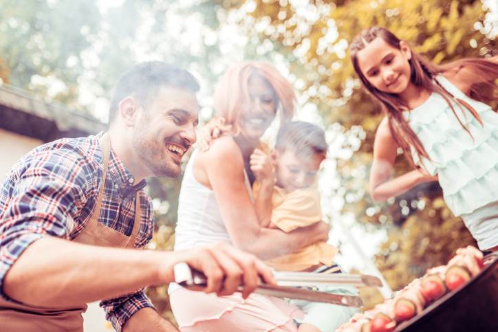 Happy young family barbecuing meat on the grill