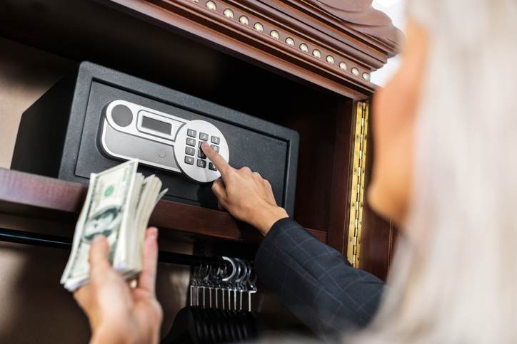Putting money in safe. Putting money in safe.