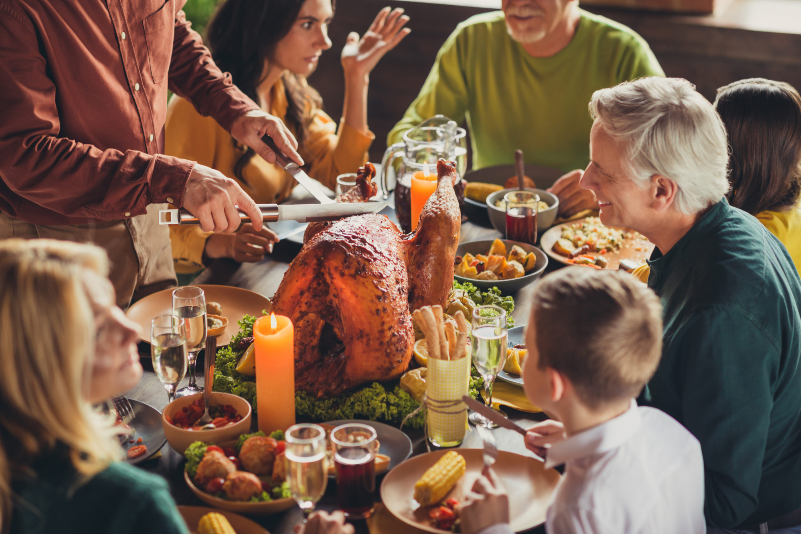 Cropped photo of family meeting served table thanks giving dinner two knives slicing stuffed turkey meal living room indoors